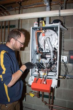 Technician working on a wall-mounted boiler unit in 